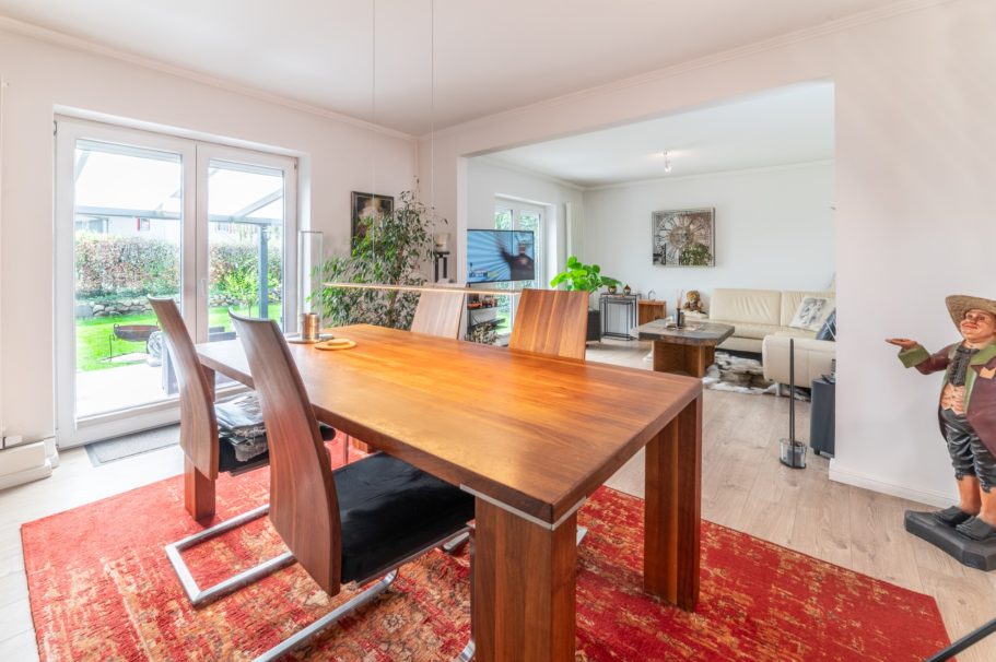 Modernes Esszimmer mit Holztisch, Stühlen und Blick auf den Garten. Stilvolle Einrichtung.