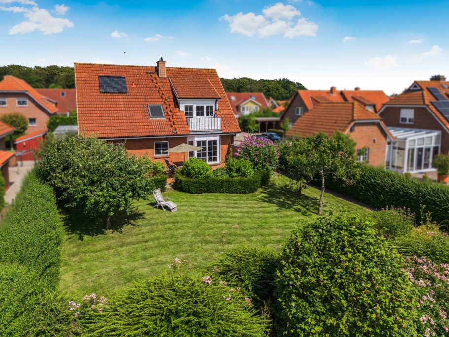 Modernes Haus mit rotem Dach und gepflegtem Garten in einer ruhigen Wohngegend.