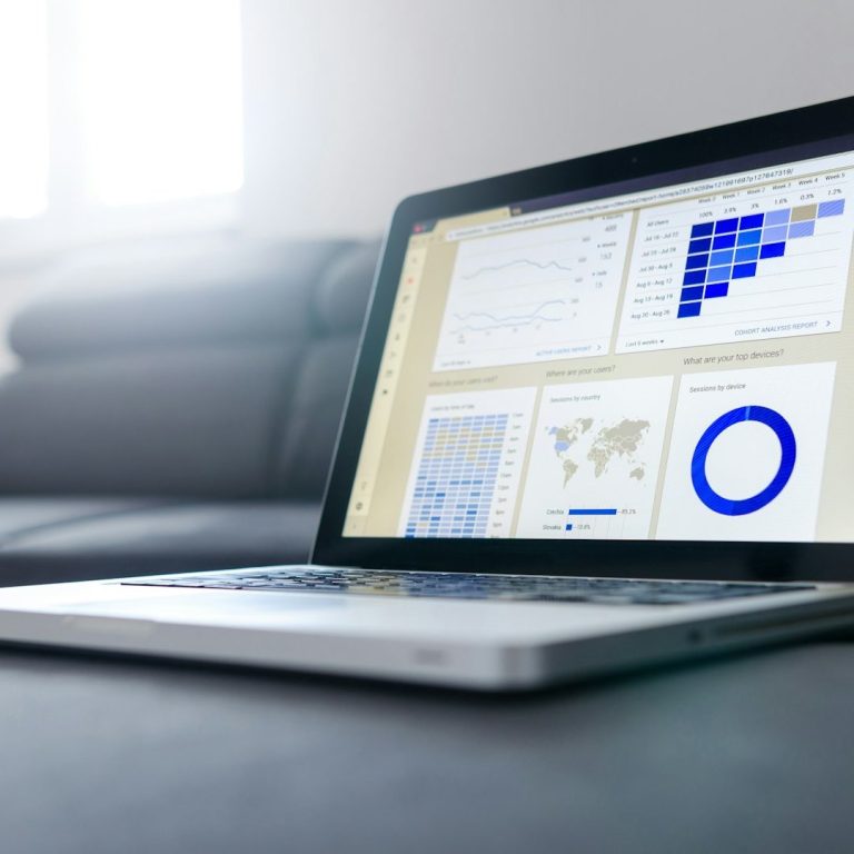 Laptop auf einem Tisch mit Datenanalysen und Grafiken auf dem Bildschirm.