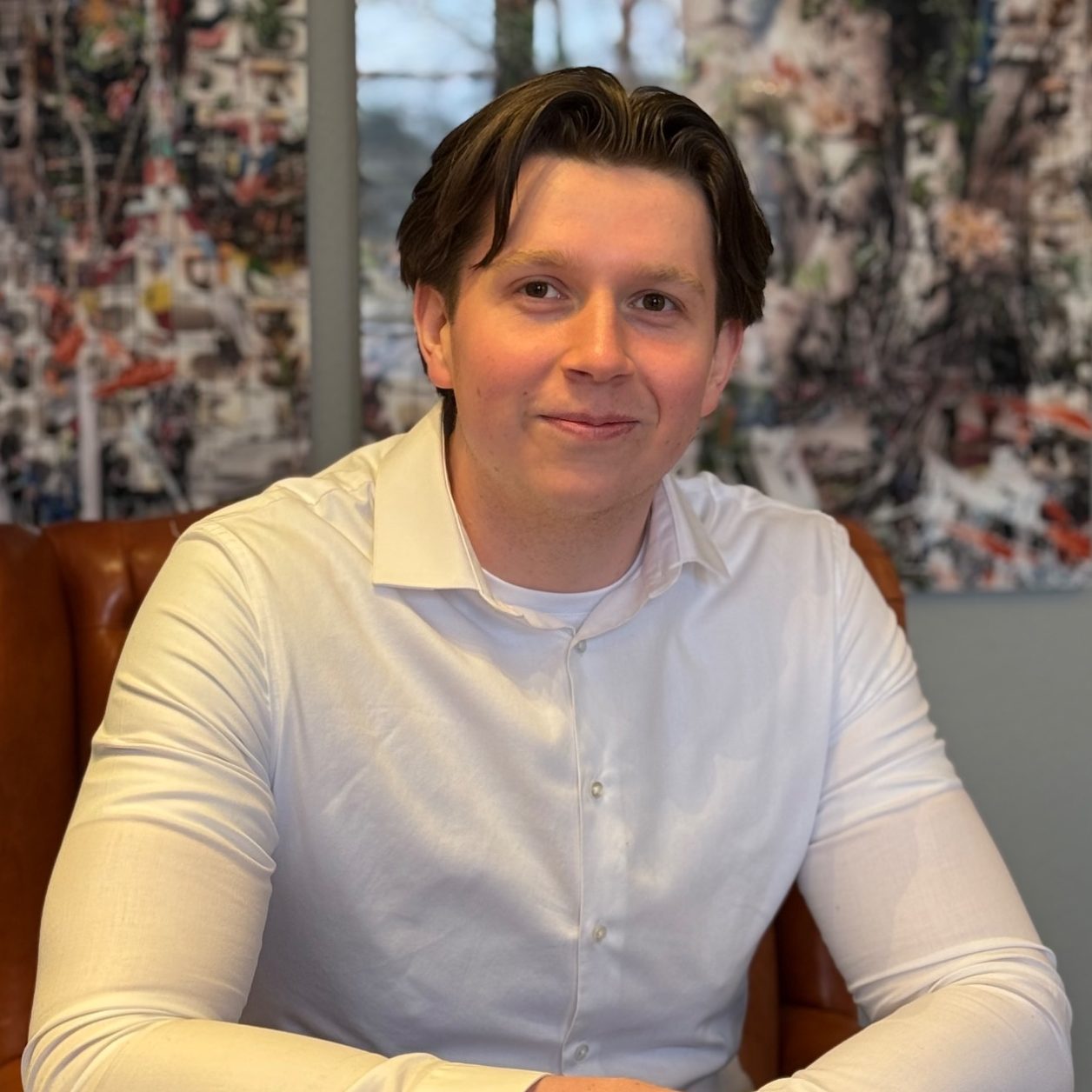 Ein junger Mann mit Glatze, Bart und Anzug schaut freundlich in die Kamera.