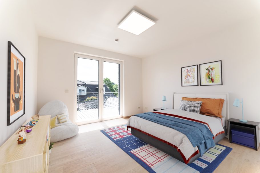 Helles Schlafzimmer mit einem Bett, buntem Teppich und zwei großen Fenstern.