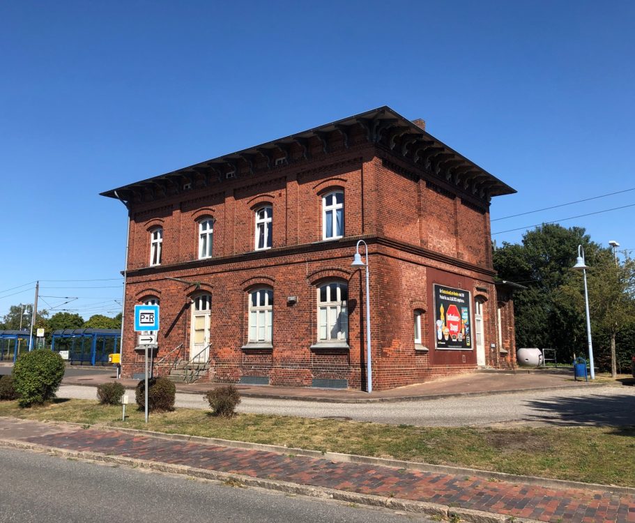 Rotes Backsteingebäude mit mehreren Fenstern und einem klaren blauen Himmel.