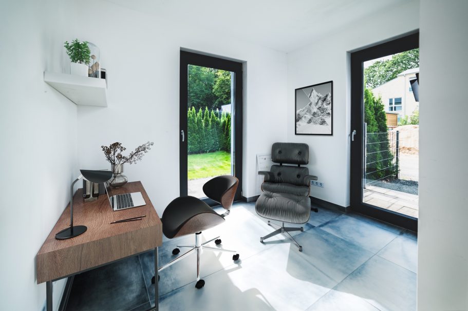 Modern Büro mit Holzschreibtisch, schwarzem Stuhl und Blick auf den Garten.
