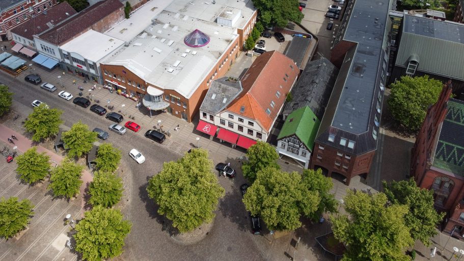 Luftaufnahme einer Stadt mit Blumenbäumen, Gebäuden und geparkten Autos.