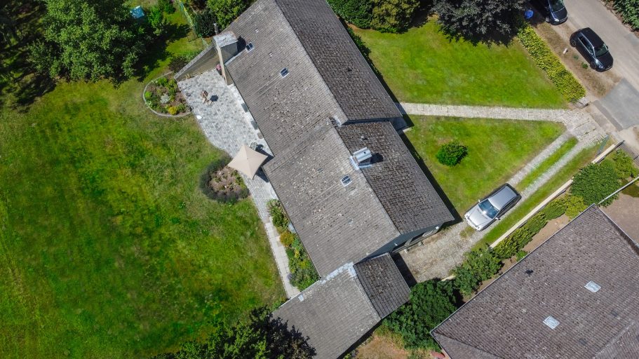 Dachansicht eines Wohnhauses mit Garten und Zufahrtswegen.