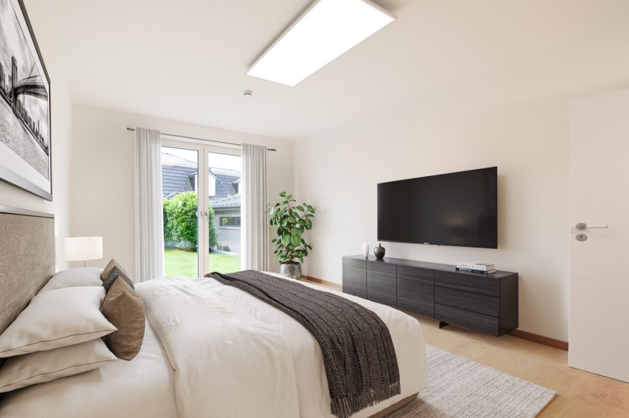 Helles Schlafzimmer mit Doppelbett, großer Fensterfront und modernem Fernseher.