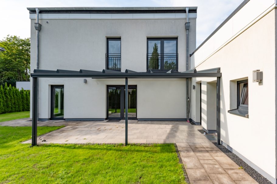 Modernes zweigeschossiges Haus mit großer Terrasse und Garten.