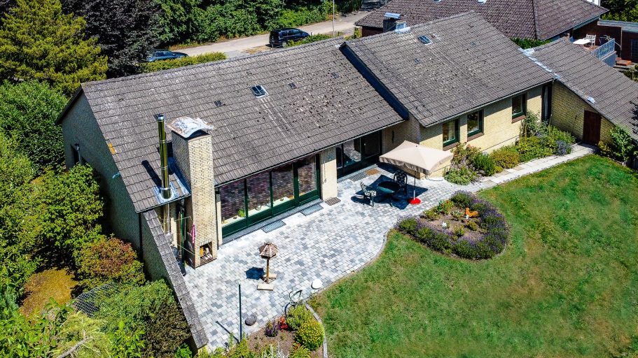 Ein modernes Einfamilienhaus mit Garten und Steinweg, umgeben von Bäumen.